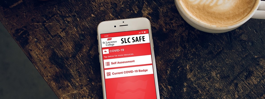 A cell phone lays flat on a wood table beside a cup of coffee. On the phone screen is the SLC Safe app.